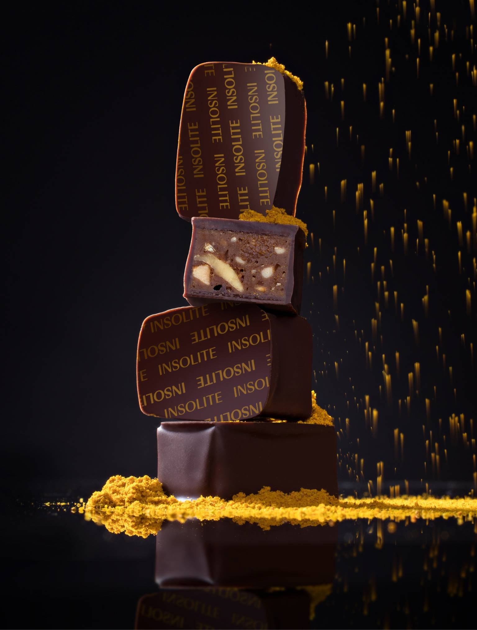 close up photo of dark chocolate bonbons with curry powder falling from above